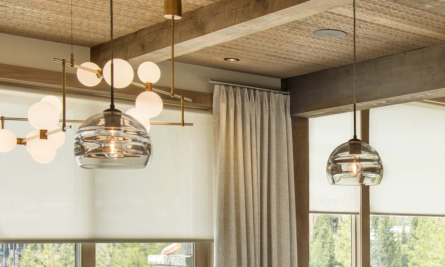 Glass pendant lights and Lutron roller shades in a wood-beamed room.